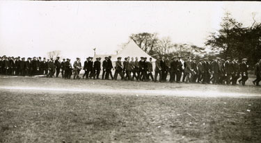 New recruits in civilian dress lined up in front of tents in Heaton Park