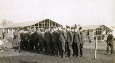 Men, some in uniform and some in civilian dress, outside half built in Heaton Park