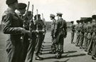 View: MR01482 Captain R G Clutterbuck accompanied by 2nd Lieutenant Saunders (Guard Commander) inspecting the rifles of the Guard in the parade ground before marching off.