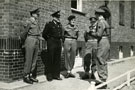 View: MR01483 Captain R G Clutterbuck (with cane) talking to L to R - 2nd Lieut Bonner, a police inspector, CSM Hill (A Company), and Major Edwards (A Company).