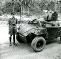 View: MR01744 2nd Lieutenant Robert Owen standing beside a Dingo Scout car with additional armour for a Bren gun